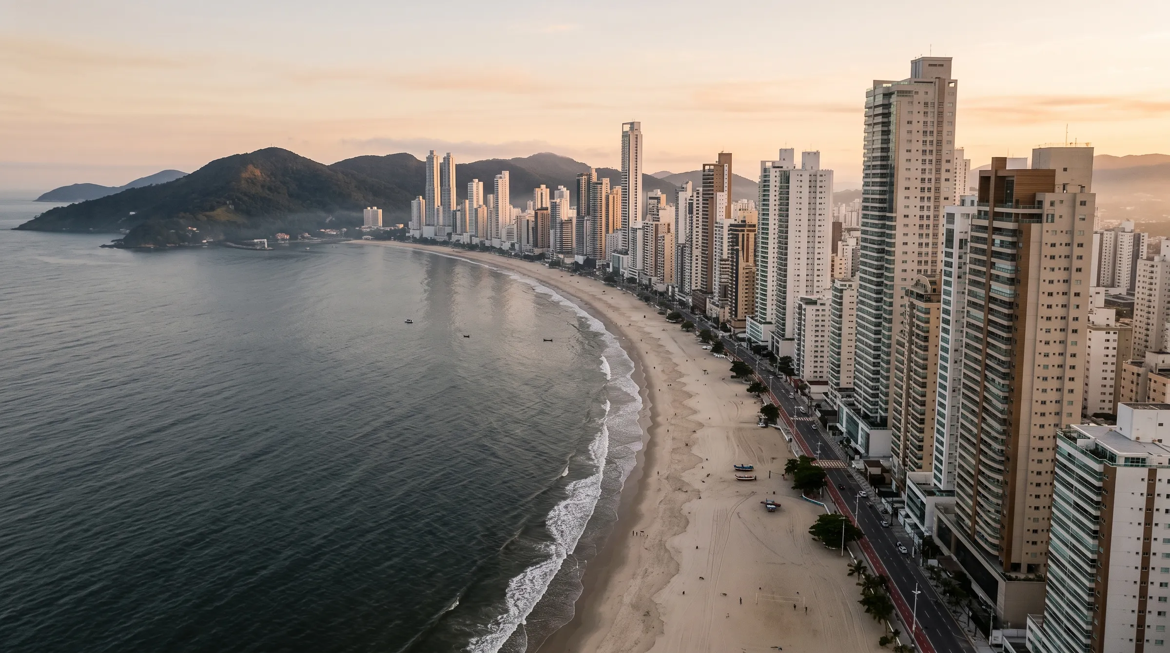 Vista aérea de Balneário Camboriú ao amanhecer: a orla curva da Praia Central e a muralha de arranha-céus